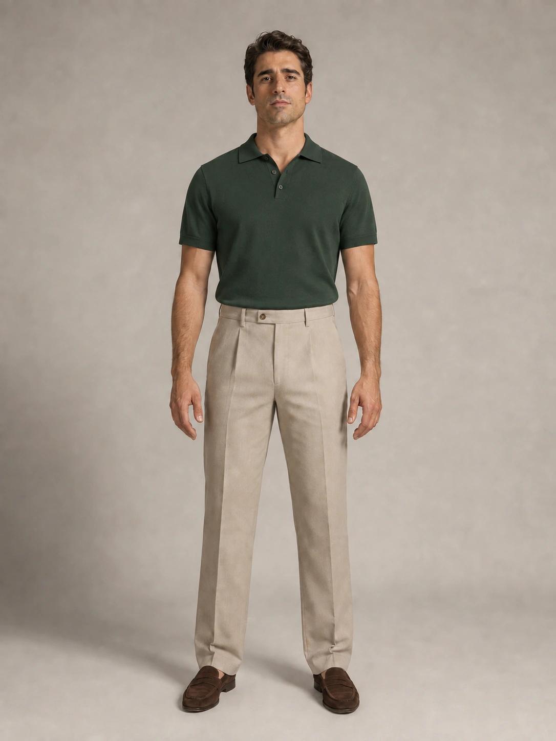 The same FIT model in a forest-green knitted polo, stone pleated trousers and brown suede loafers.